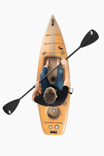 Person sitting in an inflatable kayak holding a black paddle.