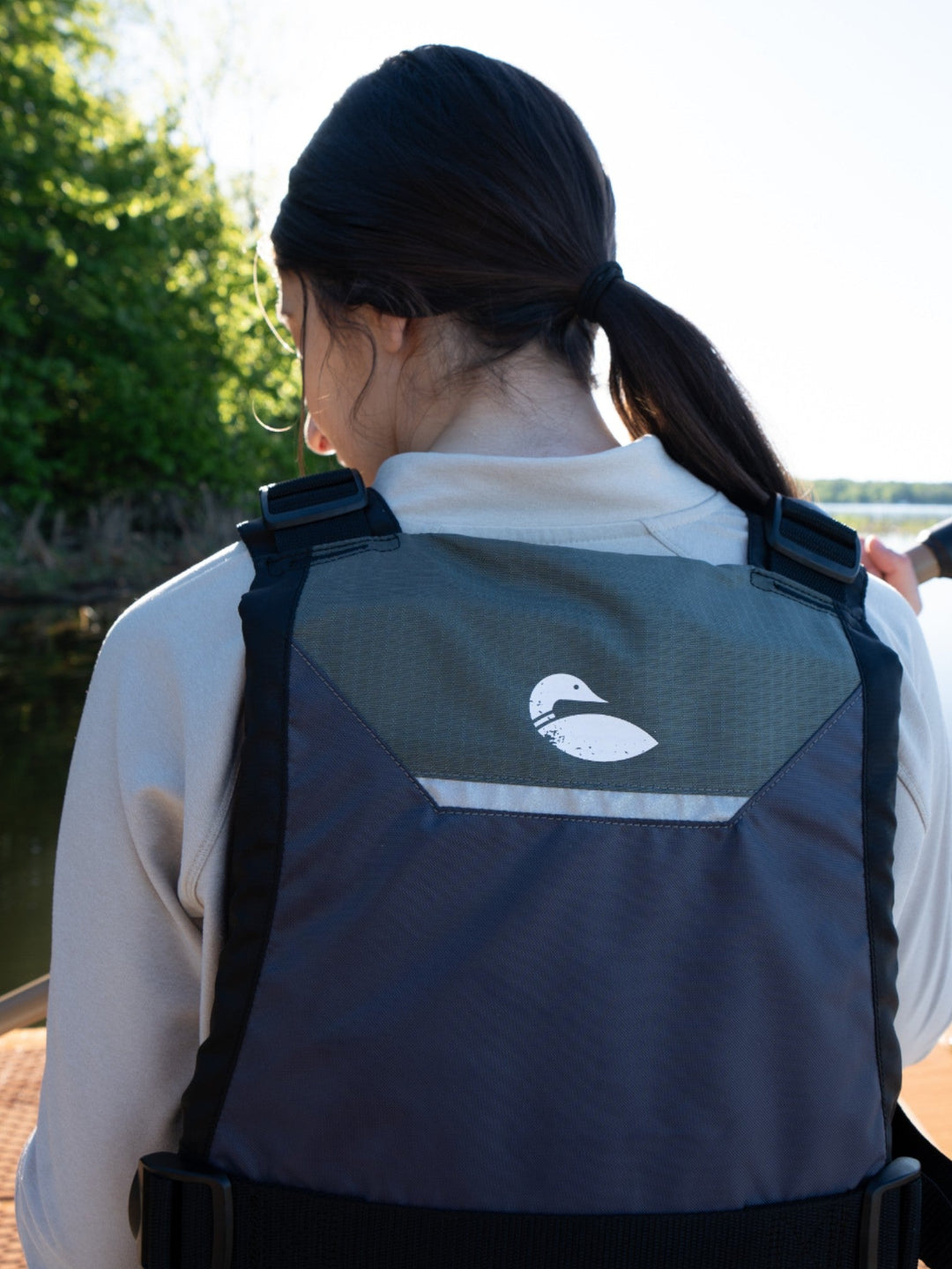 Person paddling on the water showing the back of a life vest.