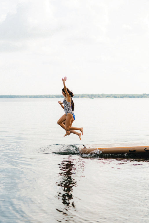 People jumping off an inflatable dock into the water.