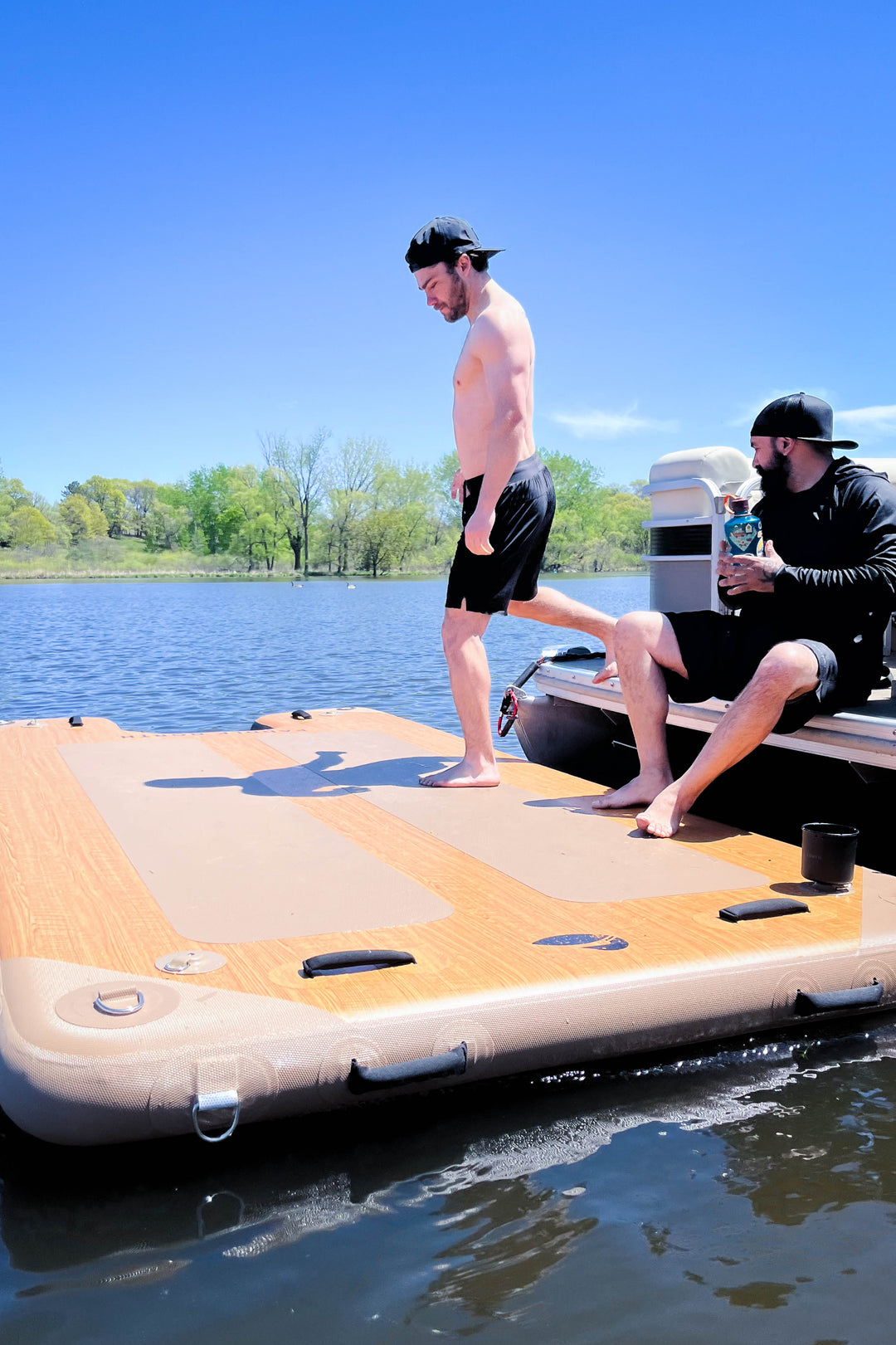 a person stepping off a pontoon onto an inflatable dock in the water.