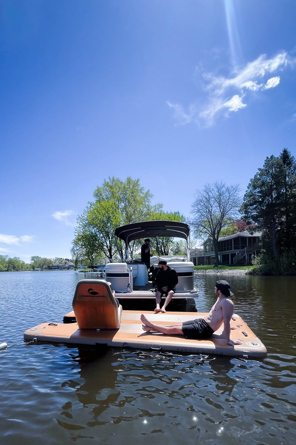 People hanging out on an inflatable dock attached to a pontoon in the water.