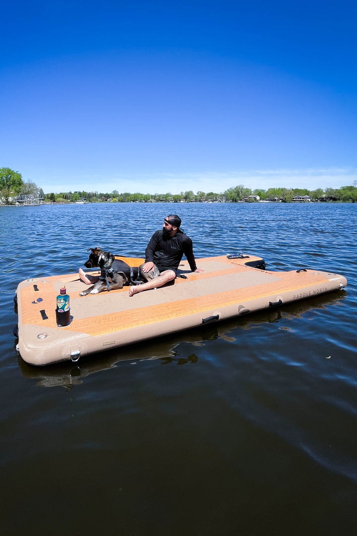 Person using an inflatable dock with a ramp beside their dog.