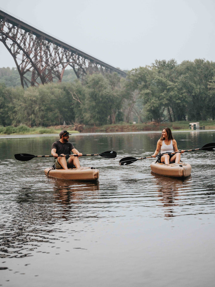 Two people kayaking in a river looking at each other.