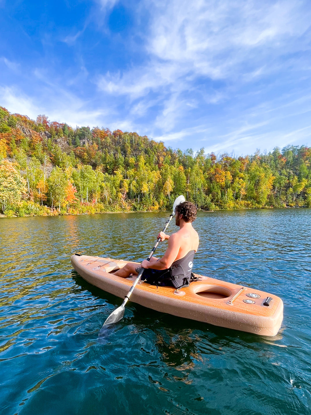 Person kayaking in water with trees in the background.