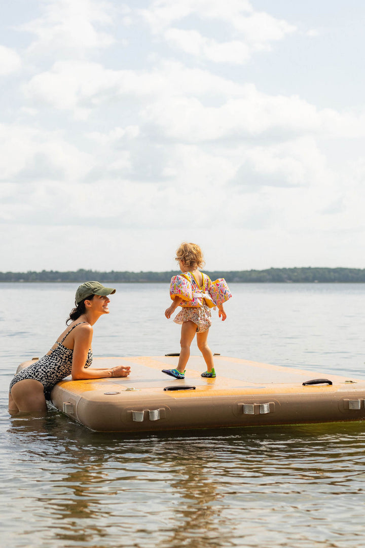 Woman in the water beside a child playing on an inflatable dock.