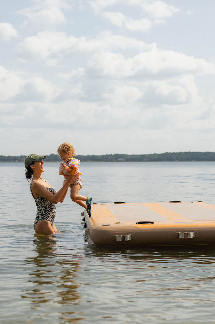 Woman in the water beside a child playing on an inflatable dock.