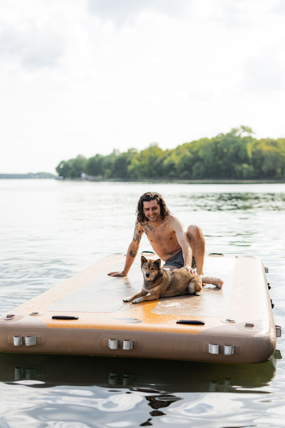 Person with their dog using an inflatable dock in the water.