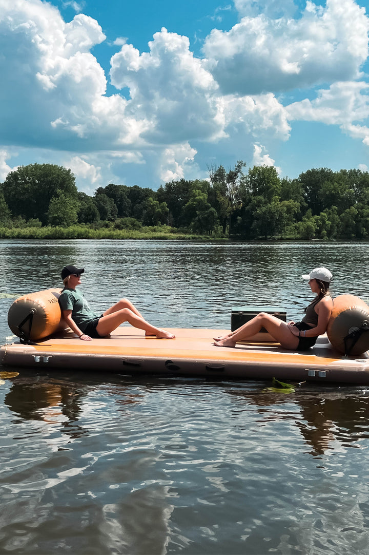 Two people on an inflatable dock using dock logs and back rests.