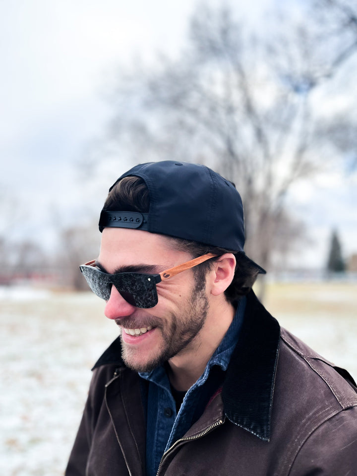 Person wearing black framed sunglasses with wood temple pieces.