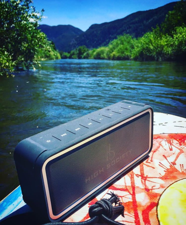 Bluetooth speaker on top of a paddle board on a river